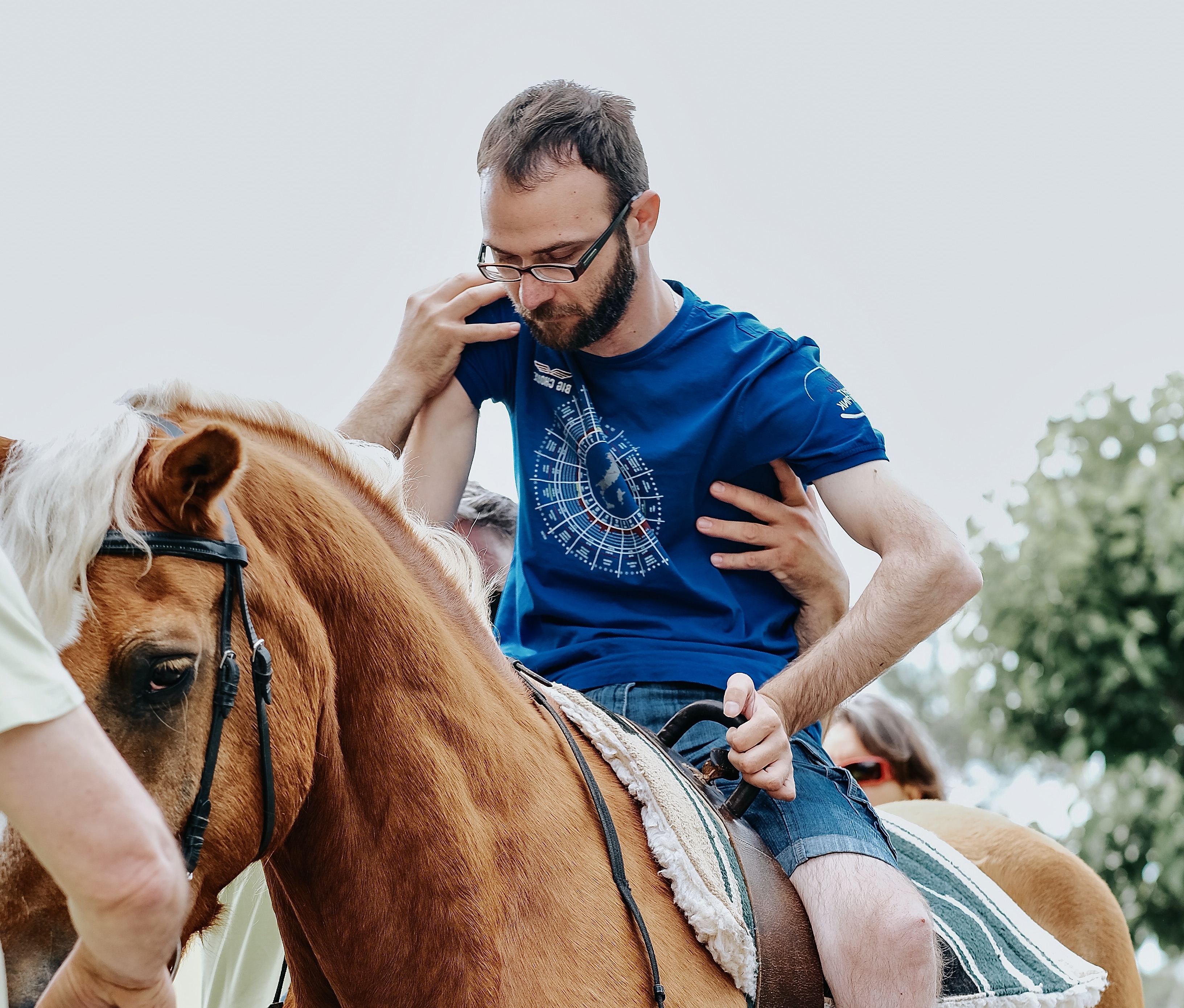 cover. Mobility impaired man on a horse. Hands of other people support him.