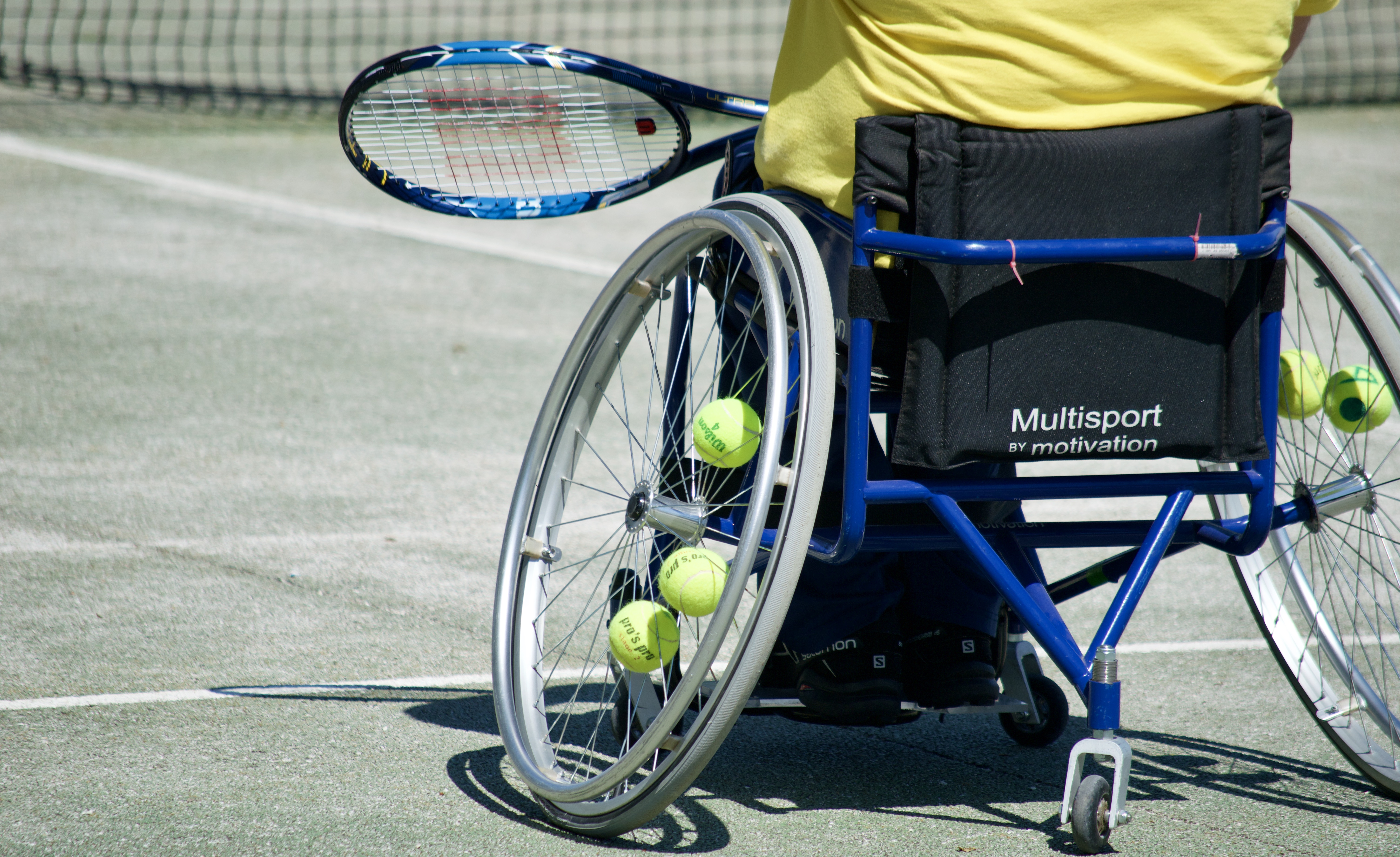 Cover. Tennis Court. Back of a tennis wheelchair in action.